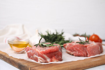 Fresh raw meat with rosemary on wooden board, closeup