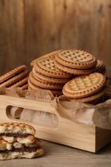 Fototapeta na wymiar Tasty sandwich cookies with cream on wooden table, closeup