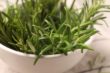 Bowl with fresh green rosemary on table, closeup
