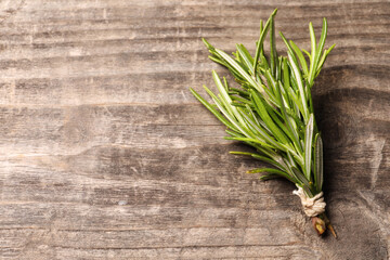 Bunch of fresh green rosemary on wooden table, top view. Space for text