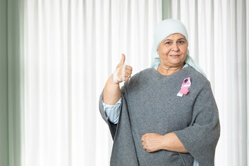 Portrait of indian senior woman cancer patient survivor standing with thumbs up at hospital after...