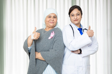 Portrait of indian senior woman cancer patient and doctor do thumbs up gesture standing at hospital, Healthcare Concept.