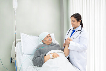 Obraz premium Indian doctor holding hand of senior patient with nasal cannula lying in hospital bed, Medical person give support and care at clinic, health care concept.