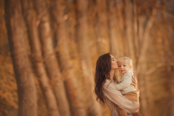 A happy family. Mom and baby. Mom gently hugs her son. Portrait of a boy. Handsome baby. Little blond. Mom kisses her son. Autumn Walk. Childhood. Son. Portrait