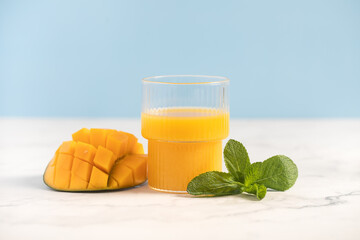 
Mango juice in a glass. tropical juice. Lemonade. Mint leaves. Blue background. Summer drink.