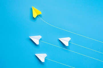 Top view of yellow paper airplane origami flying to a different direction leaving other white...
