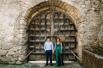 Happy couple: a young beautiful pregnant wife in a long dress and husband stand together on a sunny summer day. Man and woman in love.