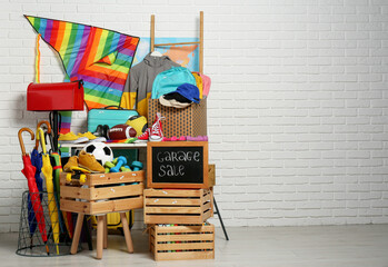 Sign Garage Sale written on blackboard near many different stuff indoors. Space for text