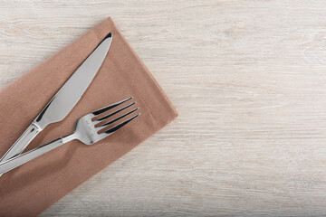 Shiny fork, knife and napkin on white wooden table, flat lay. Space for text