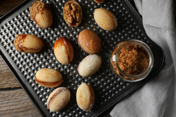 Freshly baked homemade walnut shaped cookies and topping on wooden table, top view