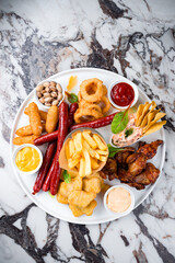 Appetizers French fries, breaded mozzarella cheese, chicken legs, onion rings coated with breadcrumbs, sausages, nuts and sauces.