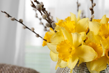 Bouquet of beautiful yellow daffodils and willow twigs on blurred background, closeup