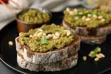 Tasty bruschettas with pesto sauce and nuts on plate, closeup