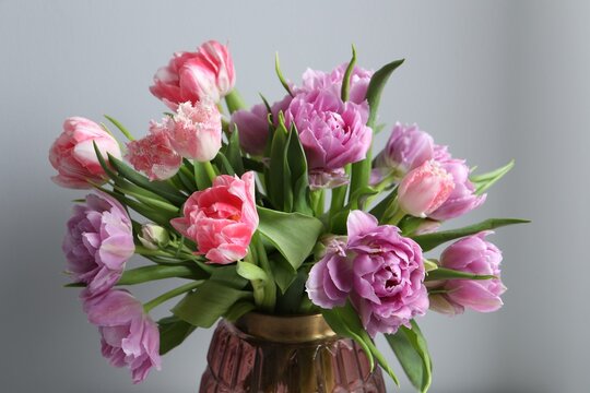 Beautiful bouquet of colorful tulip flowers near light grey wall, closeup