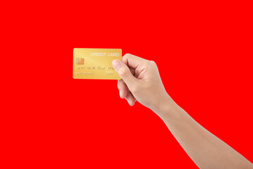 Female hand holding credit card on red background.