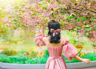 Fantasy girl princess hand touching flowers sakura tree spring nature green grass petals fall....