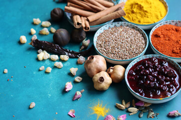 Spices and herbs on turquoise background with copy space. Food and cuisine ingredients. Colorful spices in bowls on blue background, top view