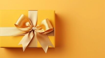 Gift box with golden satin ribbon and bow on yellow background. Holiday gift with copy space. Birthday or Christmas present, flat lay, top view. Christmas giftbox concept.