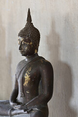 Fototapeta na wymiar The black steel Buddha image has a shadow behind it in the temple.