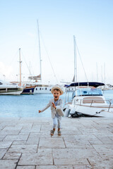 Naklejka premium Excited stylish boy running near yacht in marina