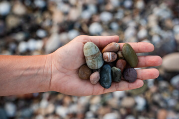Female hand with heap of pebbles on shingle beach