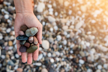 Female hand with heap of pebbles on shingle beach