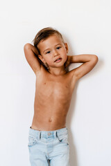Obraz premium Cute little boy wearing blue jeans posing against white background like fashion model