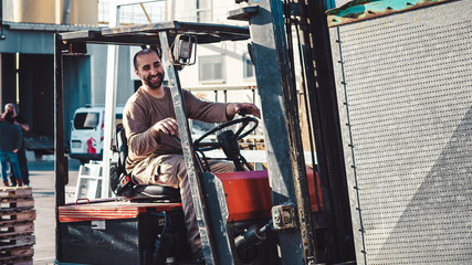 Smiling man working outside driving a forklift