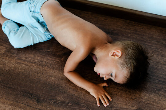 Skinny sad little boy lying on the floor