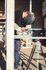 Man in protective mask welding an aluminum structure