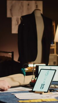 Vertical video Couturier on phone call with client talking about measurements and clothes fabric, making custom made items in fashion atelier. Business owner consulting customer for luxury suit order.