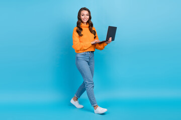 Full length photo of pretty cheerful woman wear orange sweater texting samsung apple gadget isolated blue color background