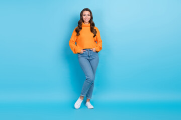Full length photo of funny adorable lady dressed orange pullover arms pockets walking isolated blue color background