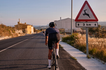 Two professional cyclist racers. Close up back view of cycling group training on a road bicycles at sunset in the mountains.Training for competition.Practicing cycling on open country road.Spain
