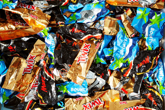 Ho Chi Minh City, Vietnam - May 10, 2023: Lots of Twix, Bounty, Mars candy empty crumpled wrappers in a pile. Popular mini chocolate bar packaging with brand logos discarded as garbage