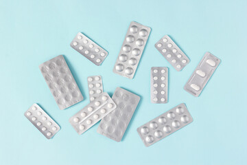 Pill blister packs on table. Top view, flat lay. Drugs, medications on blue background. Pharmaceutical products. Copy space