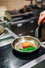 man chef cooking fried tuna fish and green bean in frying pan on kitchen