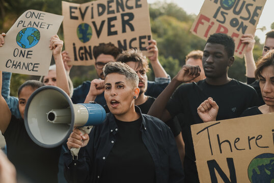 Determined diverse eco activists with carton placards and loudspeaker during demonstration on street