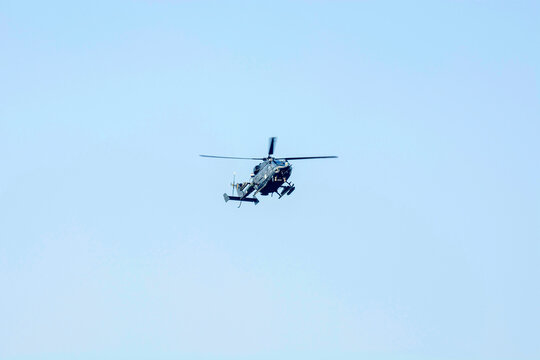 Combat helicopter is flying against isolated blue sky. Combat helicopter attack enemy.