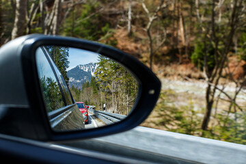 Reflection of a Mountain Road and Car in the Side Window: Adventure and Freedom of Traveling by Car