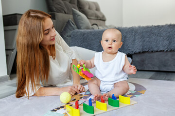 Fototapeta premium Mother and little daughter play educational games on rug in room.