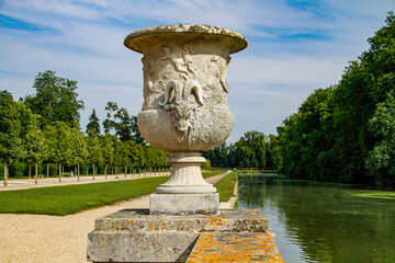 Fototapeta na wymiar Marble vase next to a long canal in the French formal garden of the Castle of Rambouillet near Paris, Yvelines, France