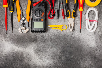 Electrician tools on black marble background.Multimeter,construction tape,electrical tape, screwdrivers,pliers,an automatic insulation stripper, socket and LED lamp.Flatley.electrician concept.