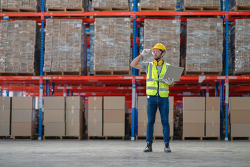 A male manager is checking inventory inside a warehouse.