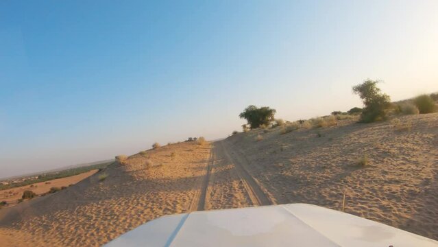 4K POV of a vehicle dune bashing on the sand dunes of the Thar desert at Jaisalmer in Rajasthan, India. Car moves on the desert during the day. Extreme adventure in the desert background.