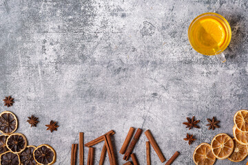 Rough gray background with cup of tea, dry oranges, dry lemons, cinnamon, and star anise. Copy space. top view