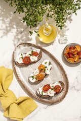 Bruschetta with mozzarella, tomatoes and thyme. Olive oil. Wooden mortar. Light background. Summer snack.