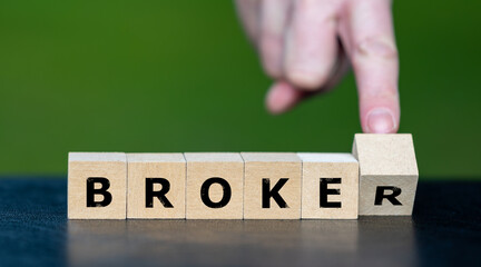 Hand turns wooden cube and changes the word broker to broke. Symbol for a wrong financial decision.