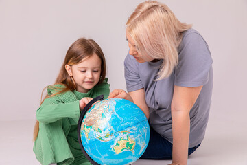 little girl learning geography with mom. Mother and daughter looking at a globe