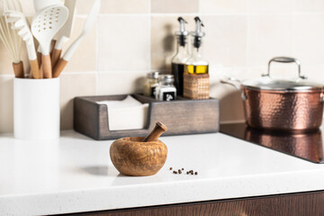 Wooden mortar with pestle. Stylish bright kitchen in the background.